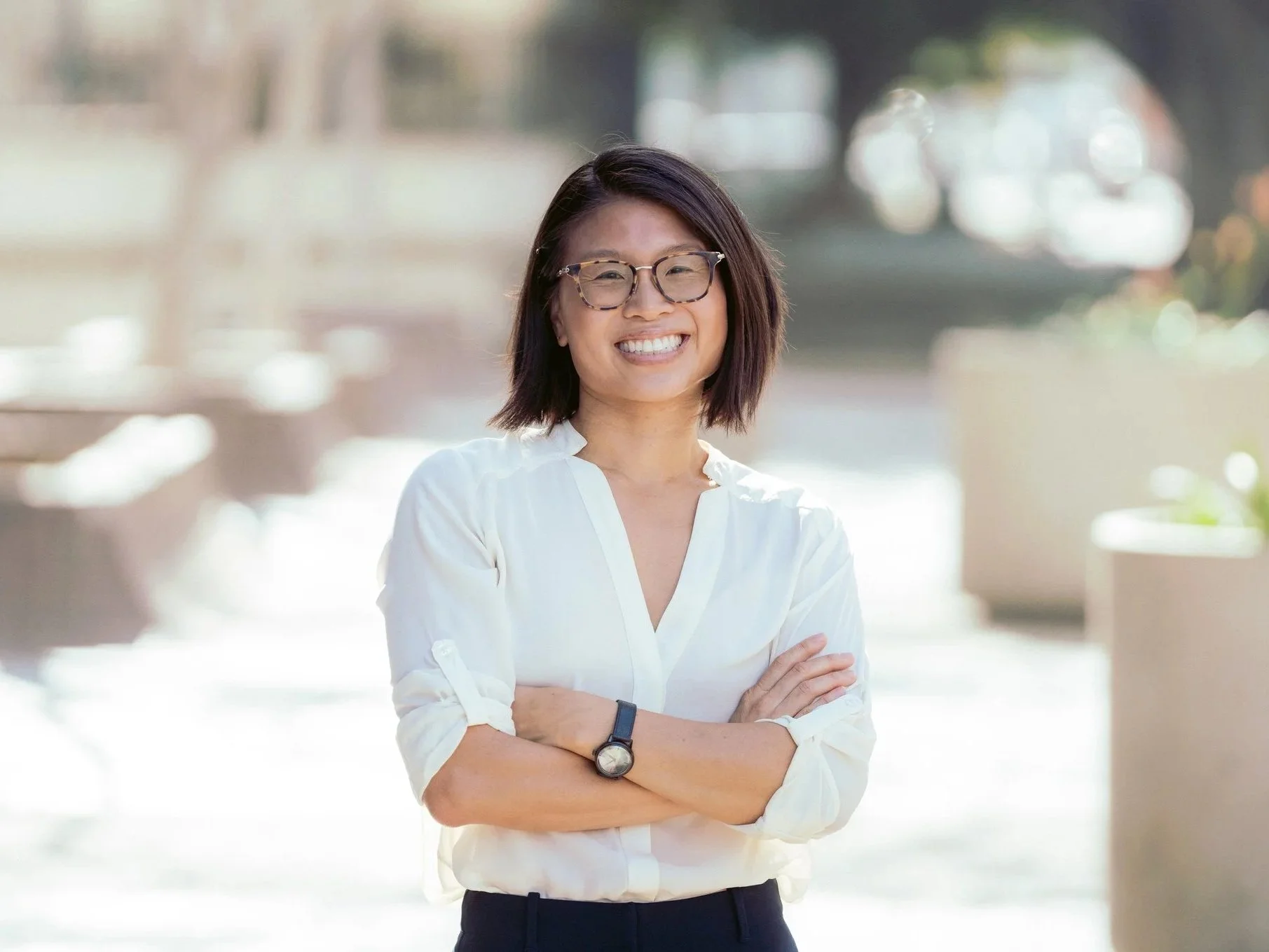 Professional photo of Rae smiling with her arms crossed outdoors